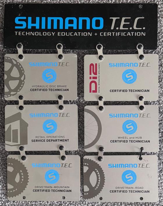 Shimano T.E.C. Technology Education and Certification plates: certified technician for Di2, hydraulic disc brakes, wheel and hub, drivetrain road and mountain, and service department operations
