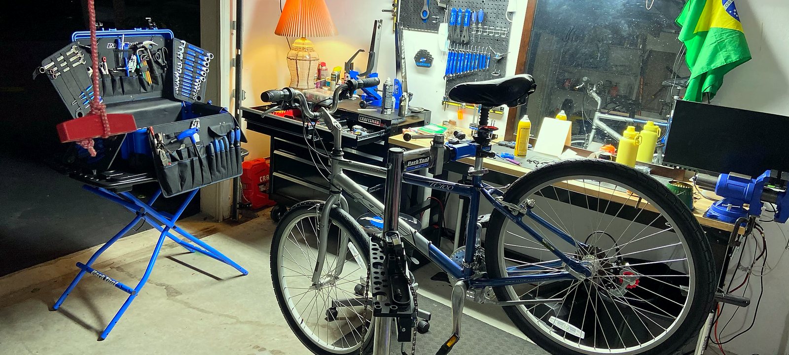 Marc Cycling workshop: a bike on a Park Tool repair stand, with the tool case, pegboard and workbench behind it.